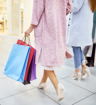 Shot of two people holding shopping bags from behind as they walk through a shopping center.
